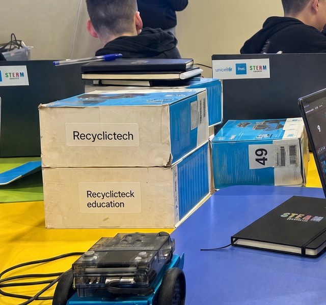 RecyclicTech-labelled cartons on a classroom table at Gimnaziul Dumitru Matcovschi, Soroca. Recipient faces are not published.
